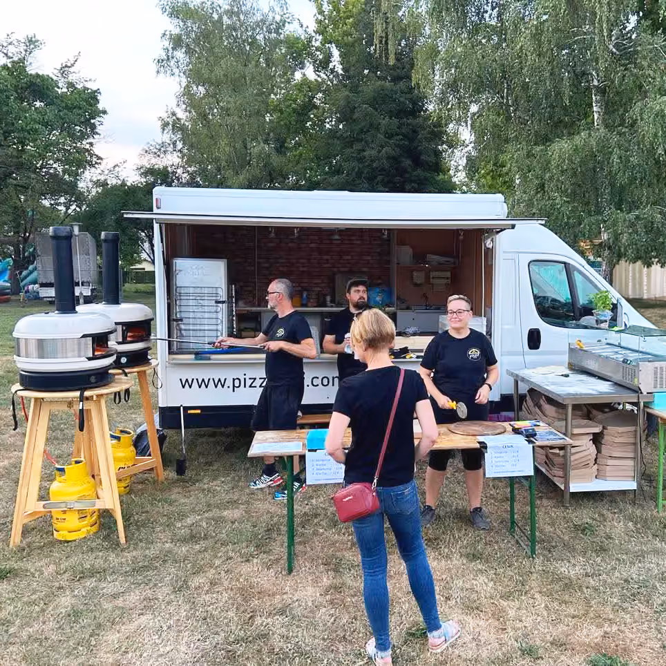 Prikolica s pečmi za pico na prireditvi, gostje pred njo