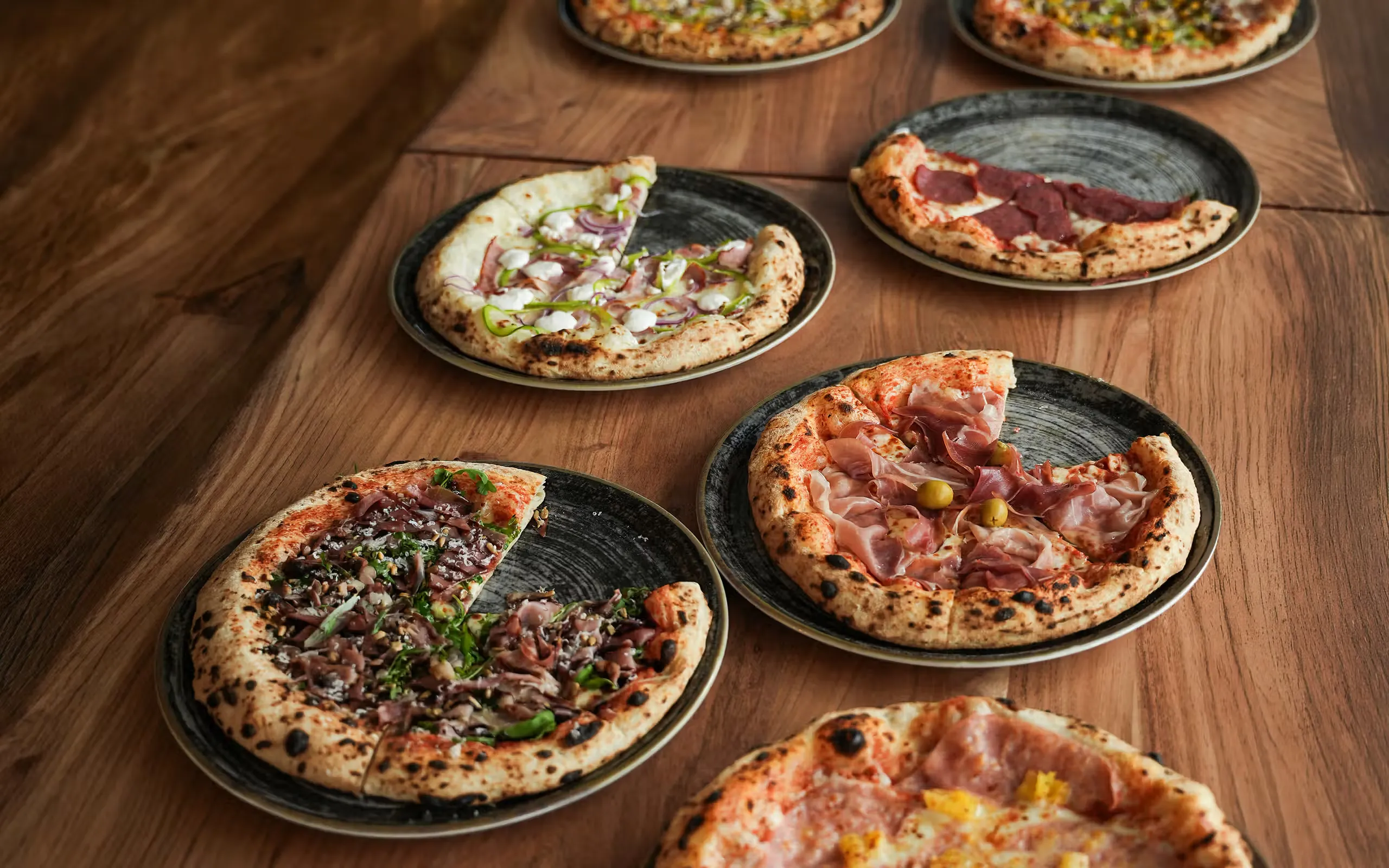 Sveže pečene pice na leseni mizi pri Pizza na i